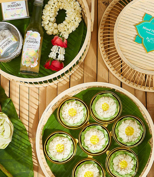 Thai New Year gift set with fragrant water, potpourri, white lotus kanom ar-lua, and fresh flower on banana leaf