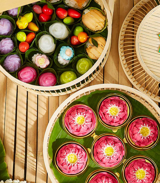 Elegant Thai dessert assortment with colorful kanom ar-lua and fruit sweets in woven bamboo trays, perfect for Songkran