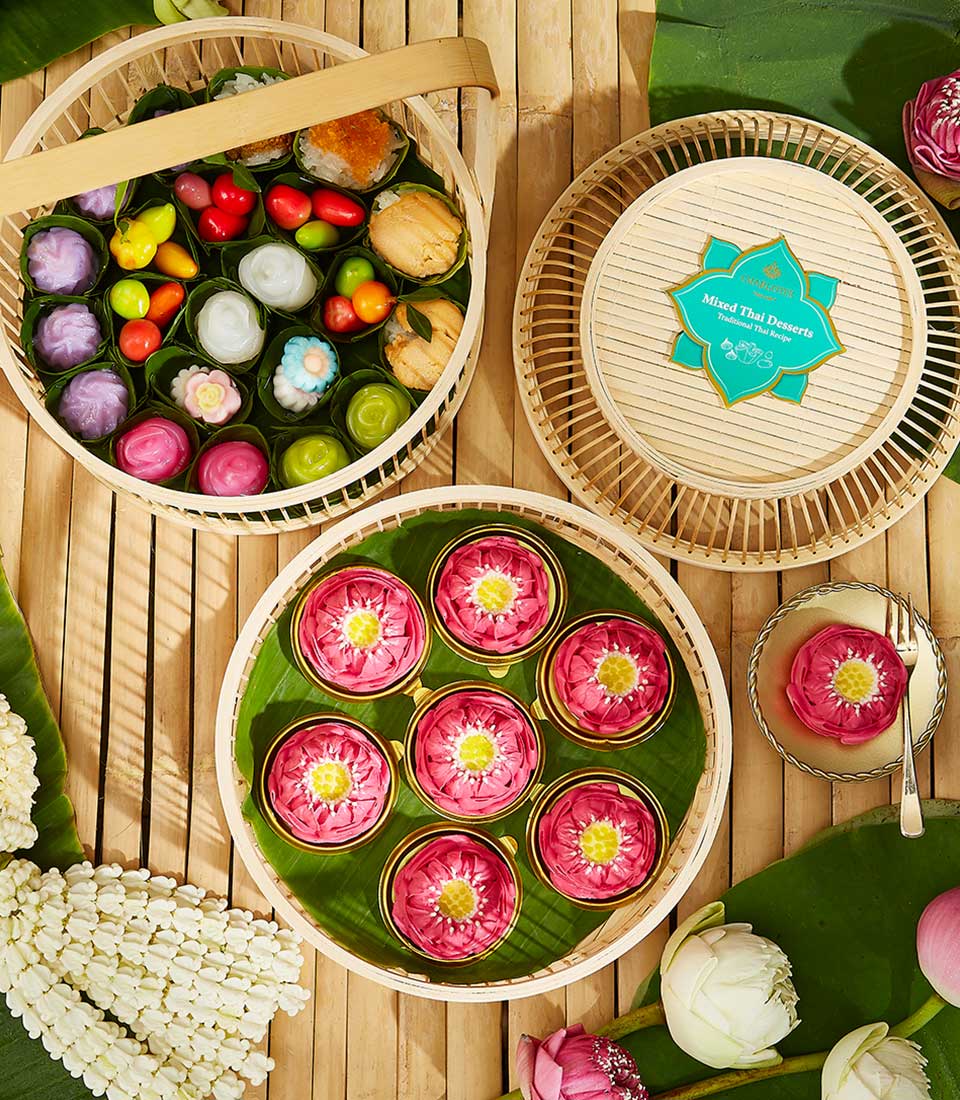Elegant Thai dessert set with luk chup and lotus sweets in bamboo basket, fresh jasmine and lotus flowers for Songkran
