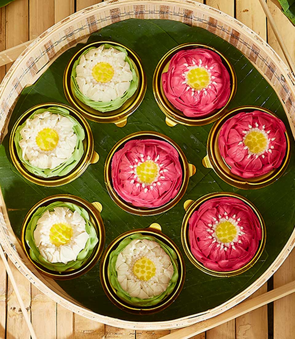 Thai lotus-shaped Kanom Ar-Lua sweet gift set on banana leaf in bamboo tray, pink and white artisan desserts for Songkran