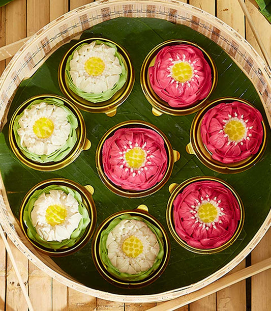 Thai lotus-shaped Kanom Ar-Lua sweet gift set on banana leaf in bamboo tray, pink and white artisan desserts for Songkran