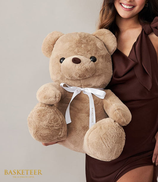 Large light brown plush teddy bear with satin ribbon bow for gifting