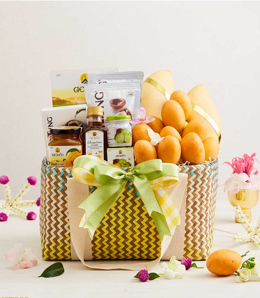 Woven chevron gift basket filled with fresh Thai mangoes, mango preserves, and gourmet treats, tied with green satin and
