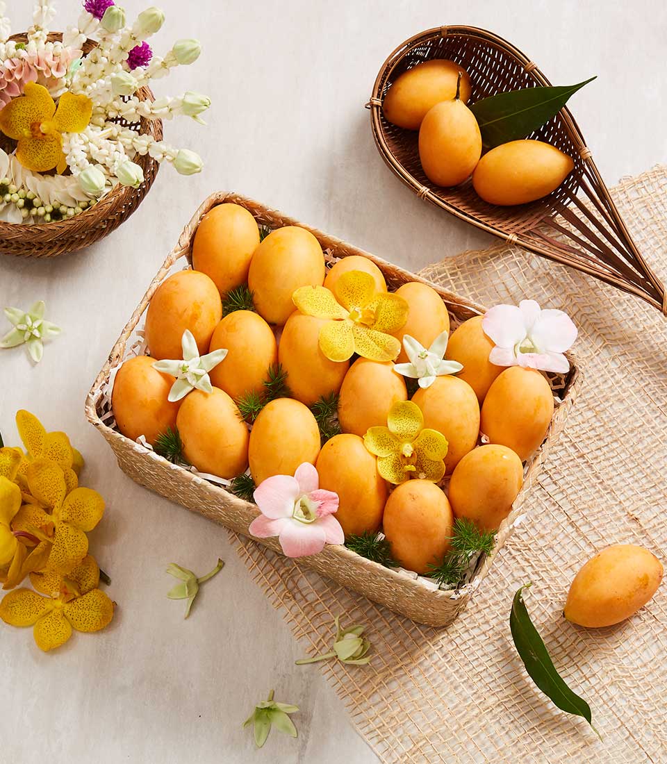 Golden-orange Marian plums in woven basket with orchids and jasmine garland