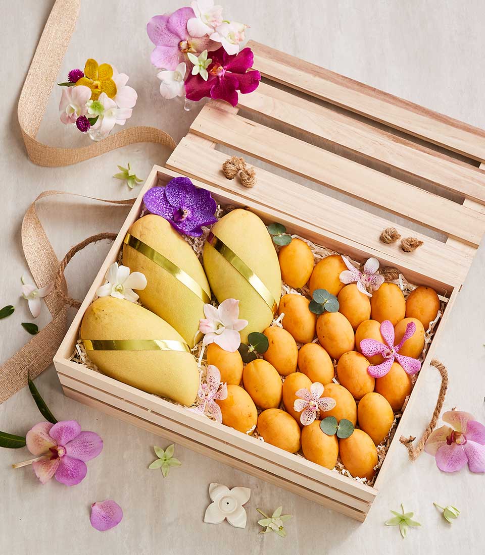 Golden mangoes and marian plum in wooden crate with orchids, luxury Thai fruit gift box