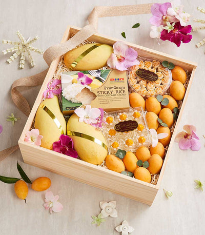 Thai mango and tropical fruit gift box with coconut cream rice, pineapple cookies, and orchid flowers in wooden presentation