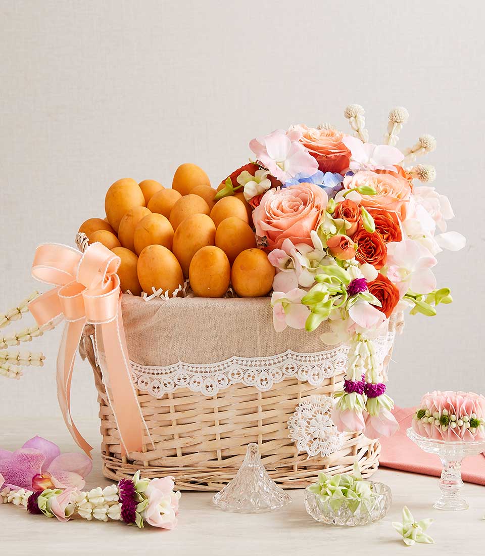 Wicker fruit and flower gift basket with plum and Thai blooms in coral and white for New Year Songkran