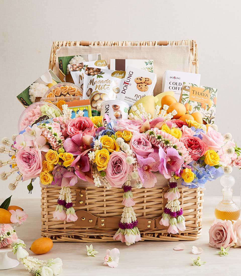 Premium Songkran gift hamper with macadamia nuts, Thai coffee, dried mango, and fresh pink roses in woven wicker basket
