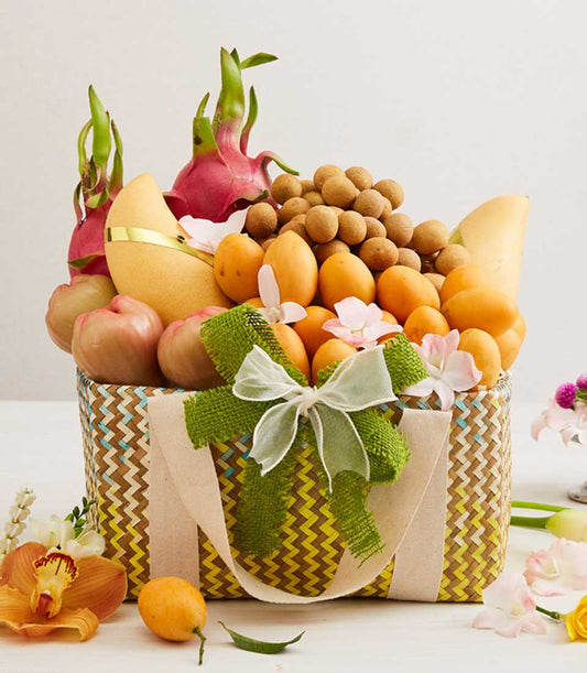 Vibrant woven chevron basket overflowing with Thai dragon fruit, mangoes, longan, and tropical fruits adorned with fresh