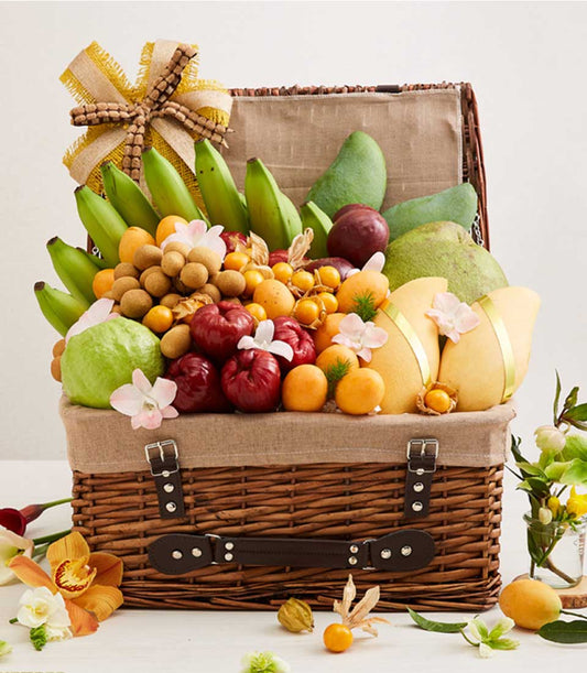 Wicker hamper overflowing with Thai tropical fruits, mangoes, guavas, and orchid blossoms, golden burlap bow