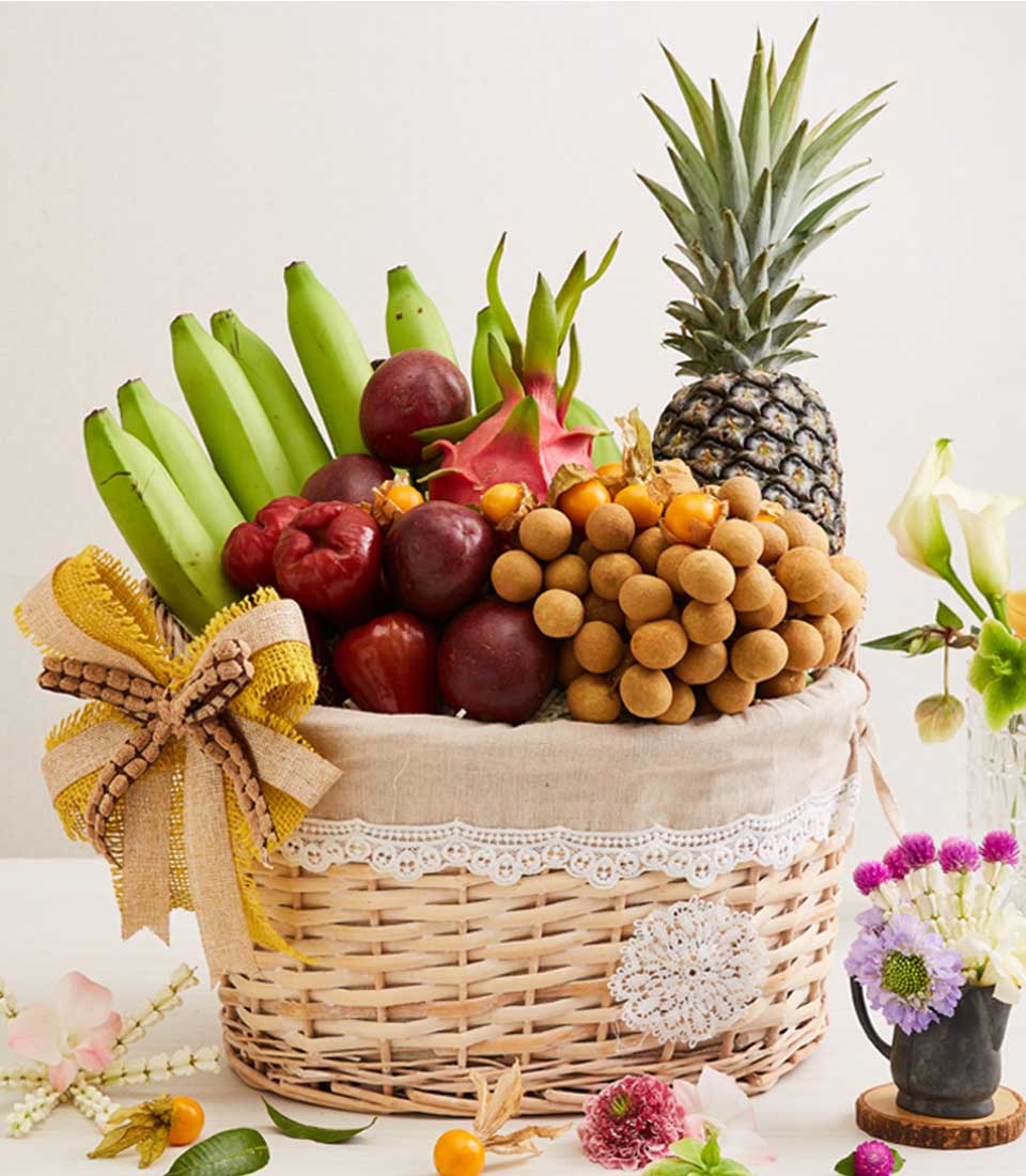 Wicker fruit basket with tropical longan, passion fruit, rose apples, pineapple, and physalis with burlap bow