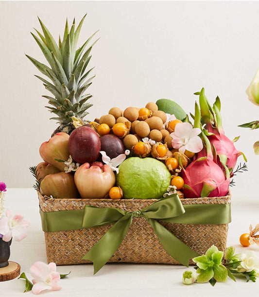 Woven rattan fruit basket with Thai tropical pineapple, dragon fruit, and seasonal produce, tied with olive-green satin