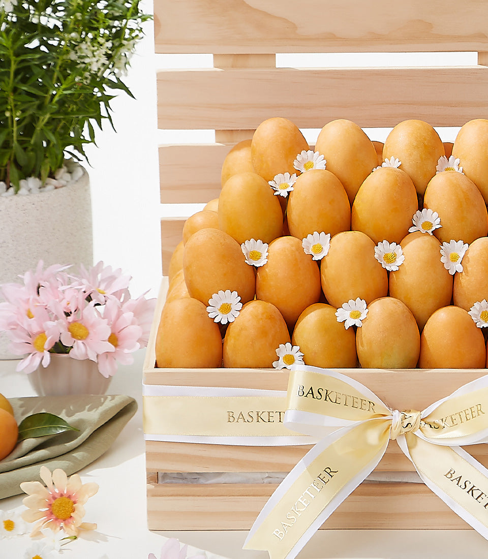Wooden crate of golden Thai mangoes with white daisies and cream Basketeer ribbon bow