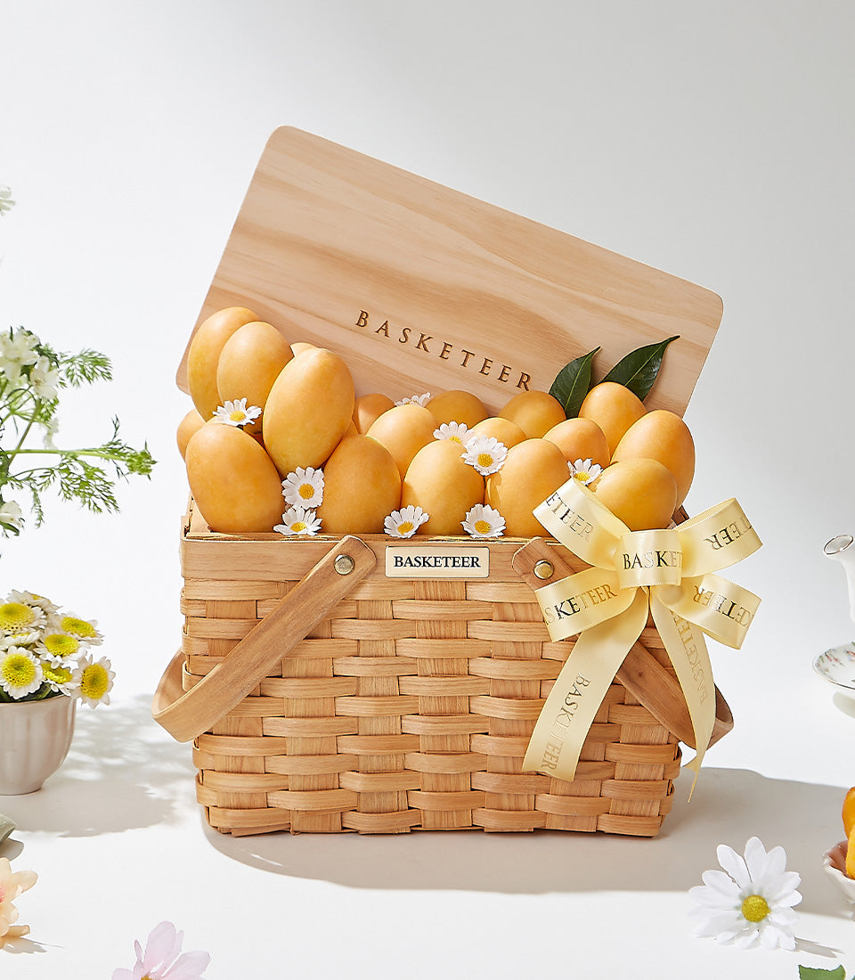 Golden mango gift basket with woven picnic design, white daisies, and wooden handle by Basketeer