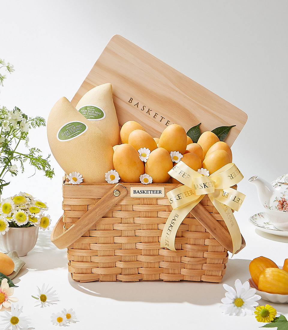 Luxe Thai mango gift basket with Mayongchid variety, woven wicker, yellow ribbon, and fresh daisies
