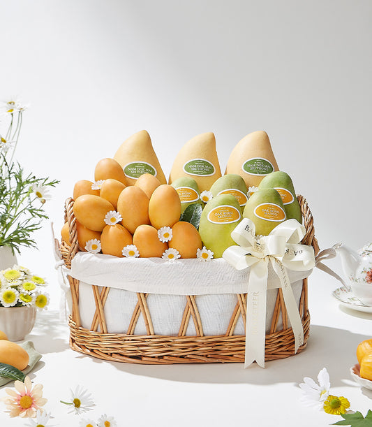 Oval wicker gift basket with white liner and cream ribbon filled with Thai Nam Dok Mai, Oak Rong, and fresh mangoes