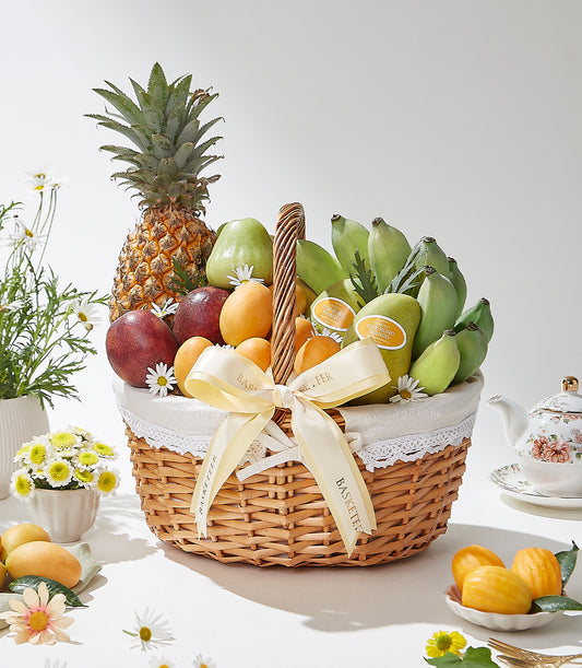 Woven wicker fruit basket with pineapple, mangoes, pears, and passion fruits, tied with yellow satin ribbon