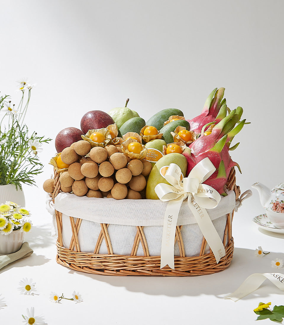 Luxury tropical fruit basket with longans, dragon fruit, mango, and passion fruit in woven wicker with cream ribbon