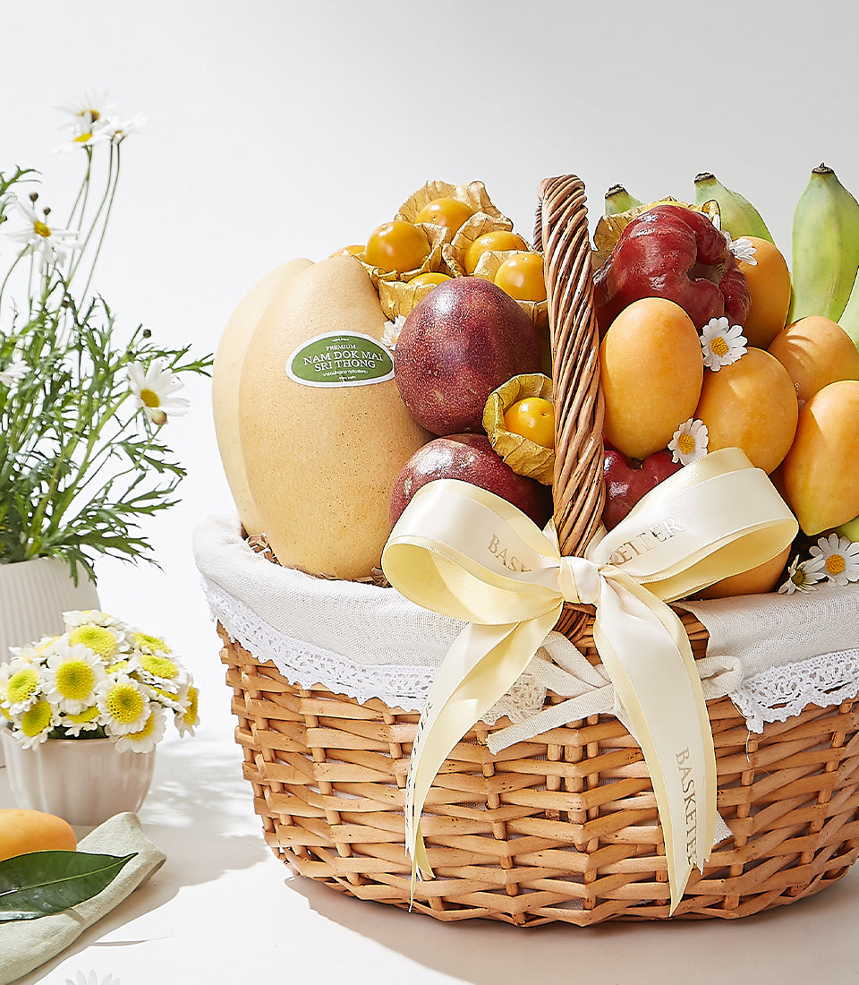 Premium woven wicker basket filled with fresh Thai tropical fruits including mangoes, rose apples, passion fruits, and