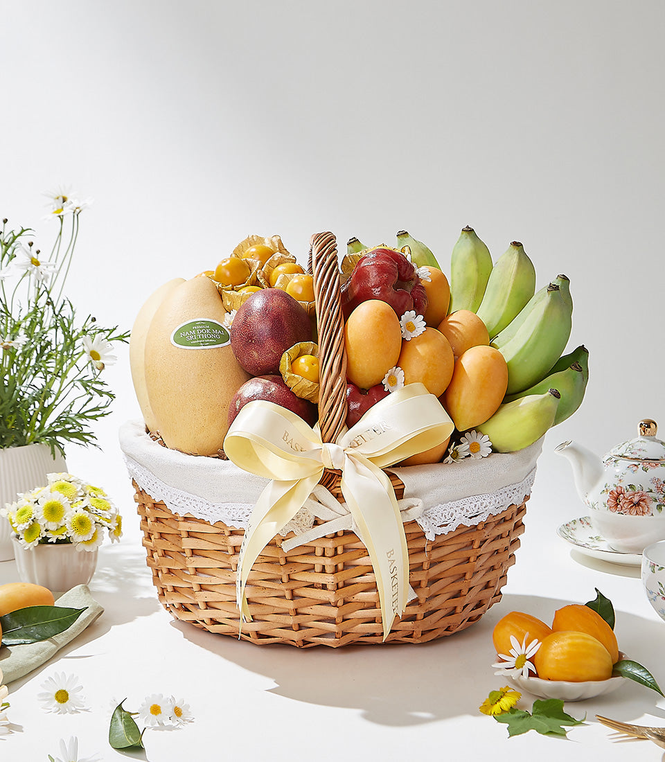 Woven wicker basket overflowing with fresh Thai tropical fruits, mangoes, pears, passion fruits, and physalis with white
