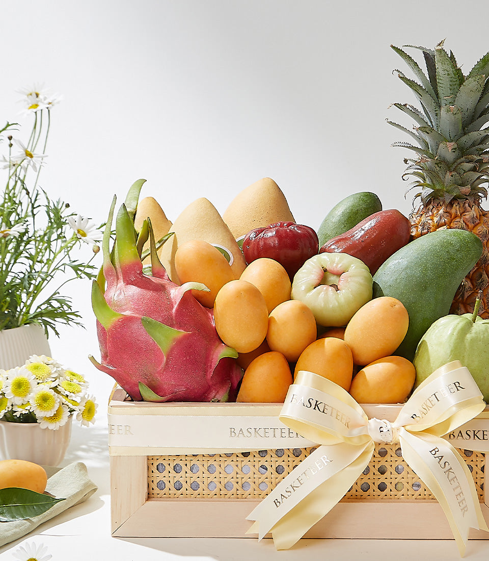 Luxury woven wood basket filled with fresh Thai tropical fruits including dragon fruit, mangoes, and pineapple, tied with