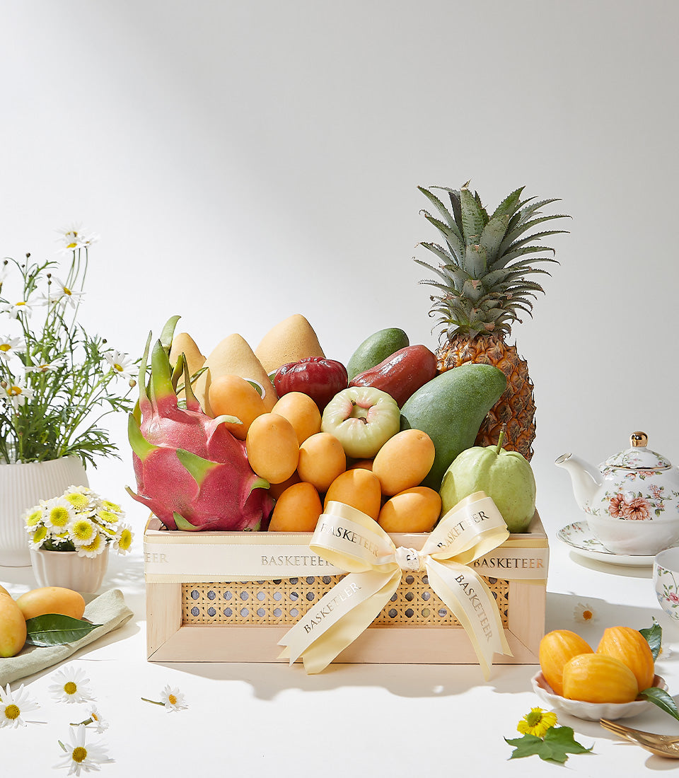 Luxury wooden fruit basket with dragon fruit, mangoes, and tropical roses apples, cream ribbon bow