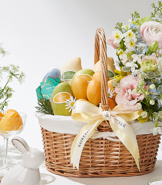 Premium wicker gift basket with Thai mangoes, sticky rice, and vibrant pink, white, and blue blooms