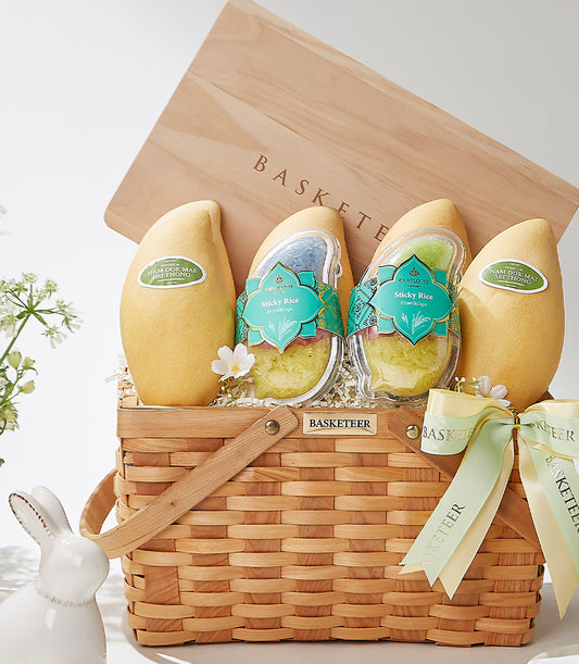 Golden tropical fruit basket with Nam Dok Mai mangoes, sticky rice, and fresh flowers in woven wood carrier