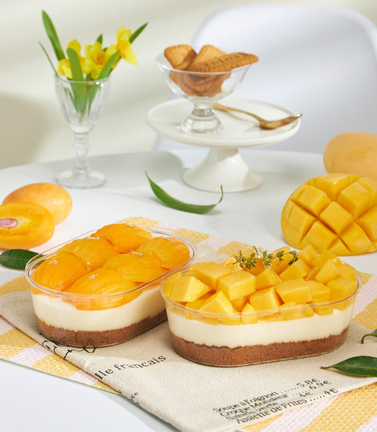 Mini mango Biscoff cheesecake in clear container with fresh sliced mango and herb garnish
