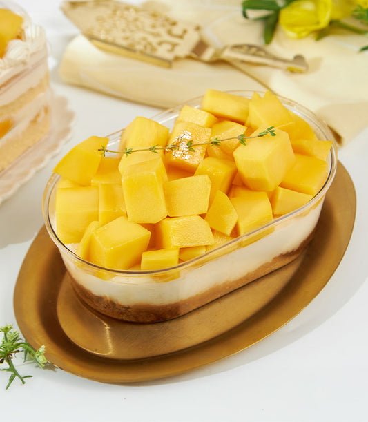 Mini mango and Biscoff cheesecake with crushed biscuit base in clear oval container, gold tray
