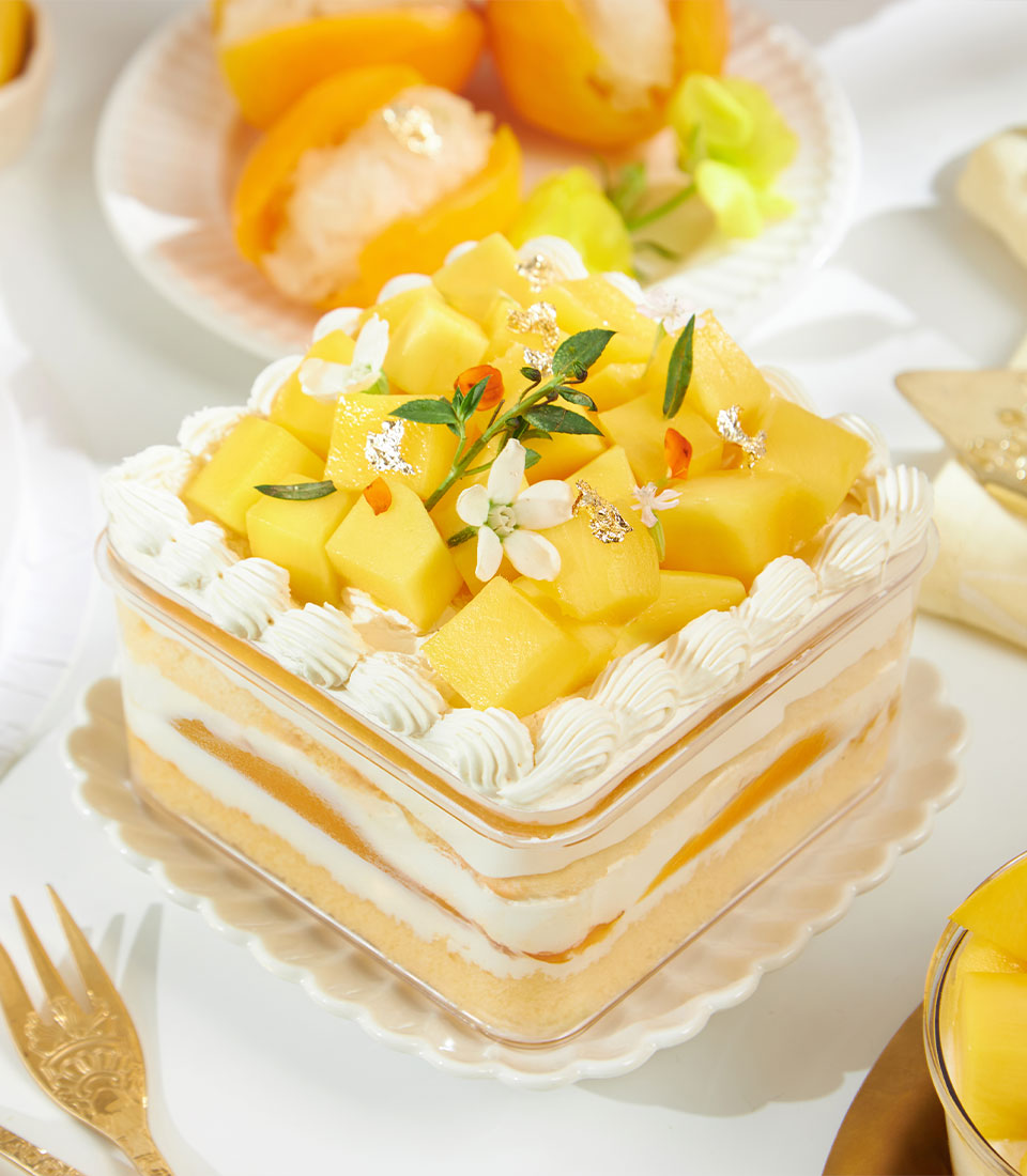 Golden mango layer cake with fresh mango pieces, edible flowers and gold leaf garnish