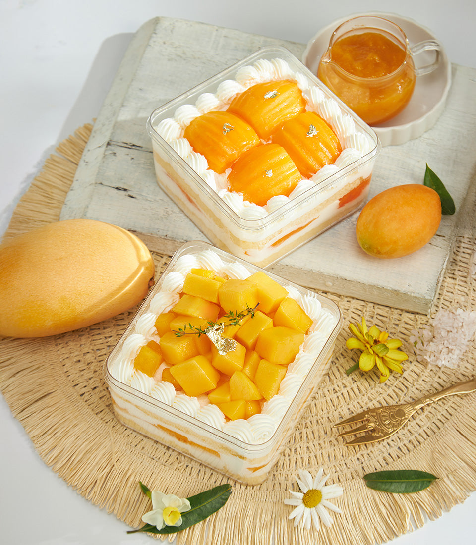 Mini mango cream cake with madeleine shapes, fresh fruit, and edible gold leaf in clear container