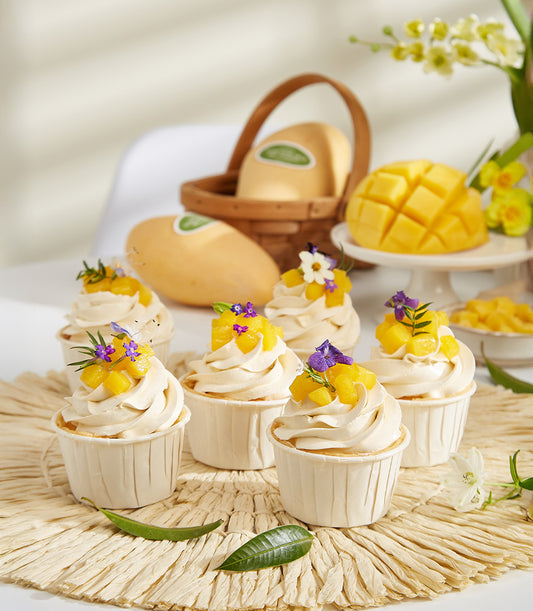 Mango Passion summer cupcakes with edible flowers, fresh tropical fruit gift set on woven mat