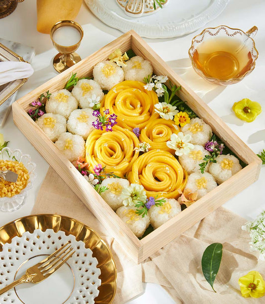 Golden mango sticky rice desserts in wooden gift box with crispy mung beans and fresh flowers