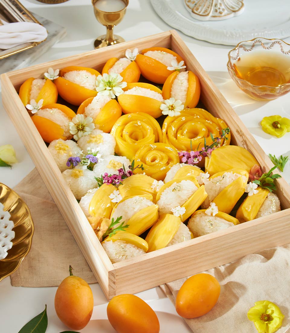 Luxury golden Thai sticky rice and fresh mango dessert box with edible flowers and gold leaf garnish