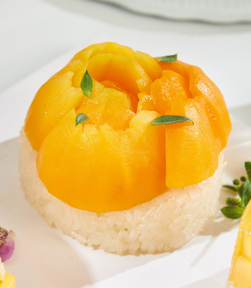 Royal Trio mango sticky rice dessert with fresh tropical fruit on white plate