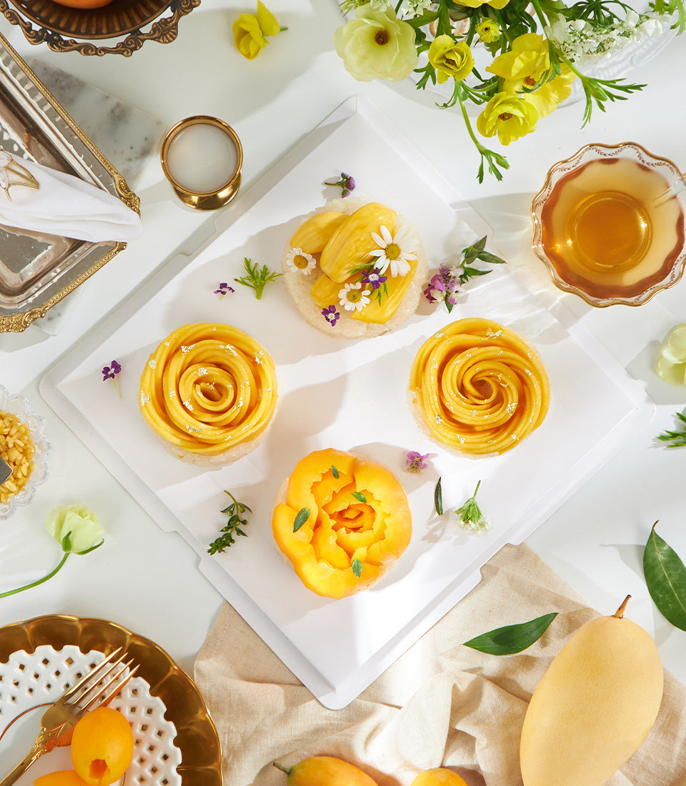Mango sticky rice desserts with edible flowers and gold leaf, tropical fruit gift collection