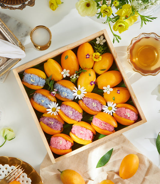 Premium mango sticky rice desserts with vibrant colored rice and gold leaf on wooden tray