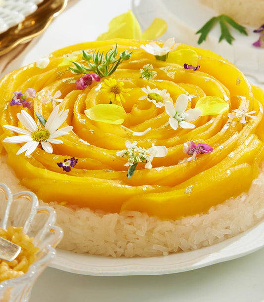 Golden rose mango sticky rice cake with edible flowers and gold leaf, artisan Thai dessert