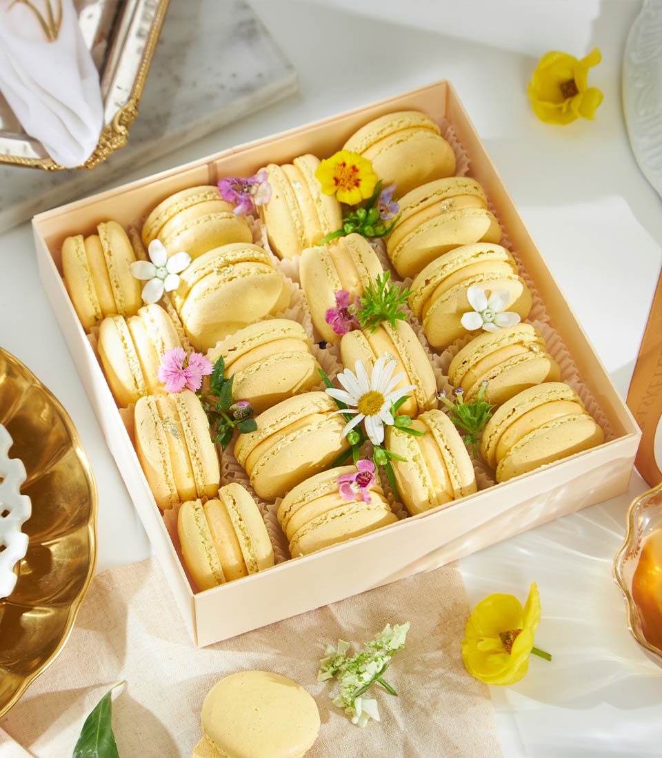 Golden mango macarons gift box with fresh flowers and creamy filling