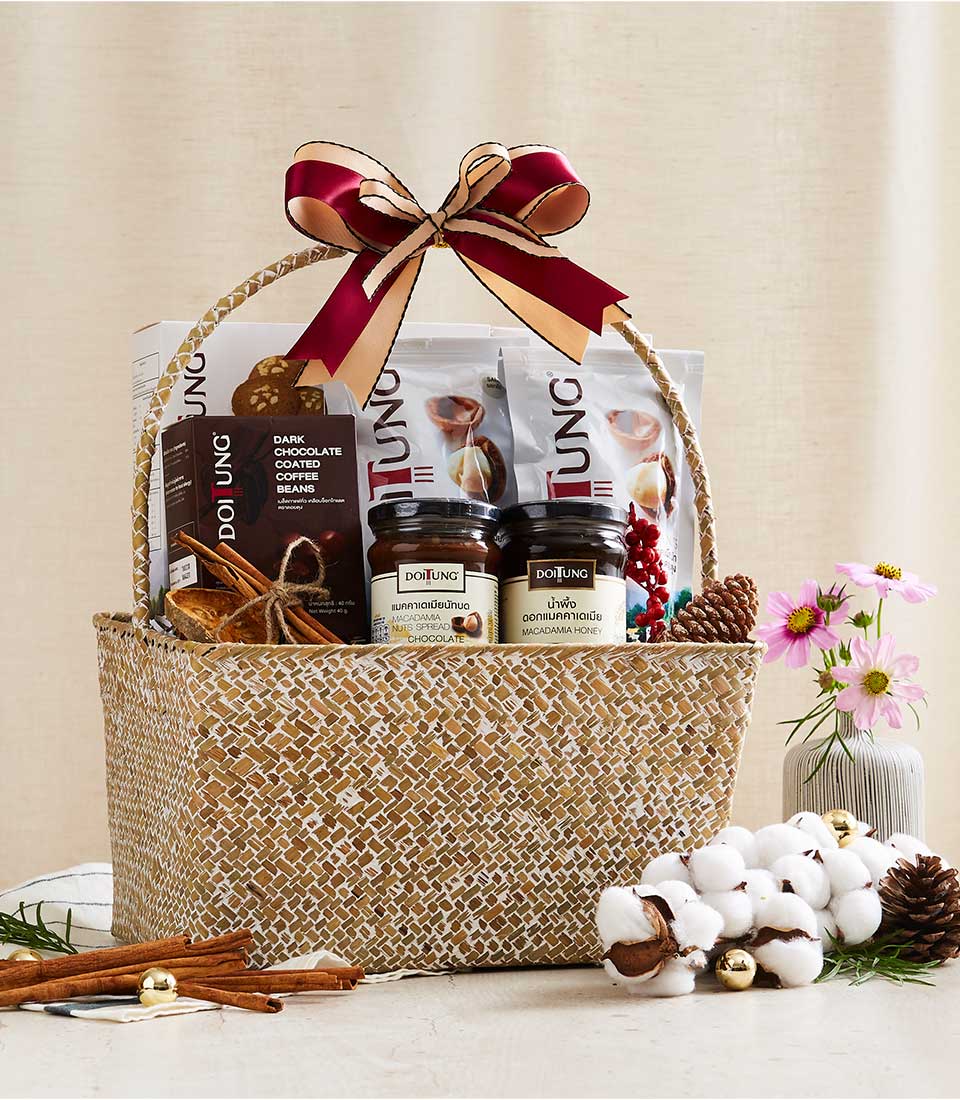 Woven rattan gift basket with burgundy and gold ribbon bow, filled with gourmet macadamia spreads, chocolate coffee beans,