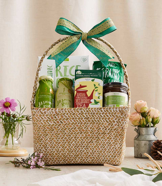 Woven natural fiber gift basket with organic jasmine rice, mulberry tea, coconut flower nectar, and grains, tied with green