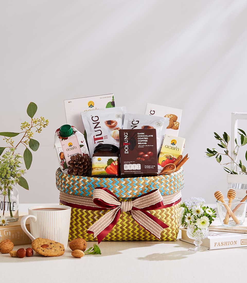 Woven gift basket with yellow and blue geometric pattern containing gourmet coffee, jam, juice, and chocolate-covered beans,