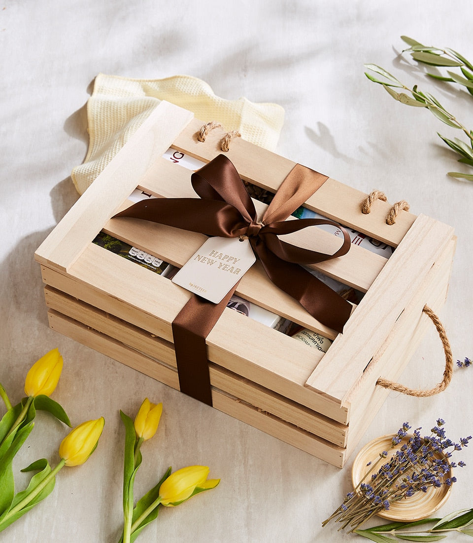 Light wooden gift crate with Doi Tung artisan collection, tied with dark ribbon and New Year tag, surrounded by yellow