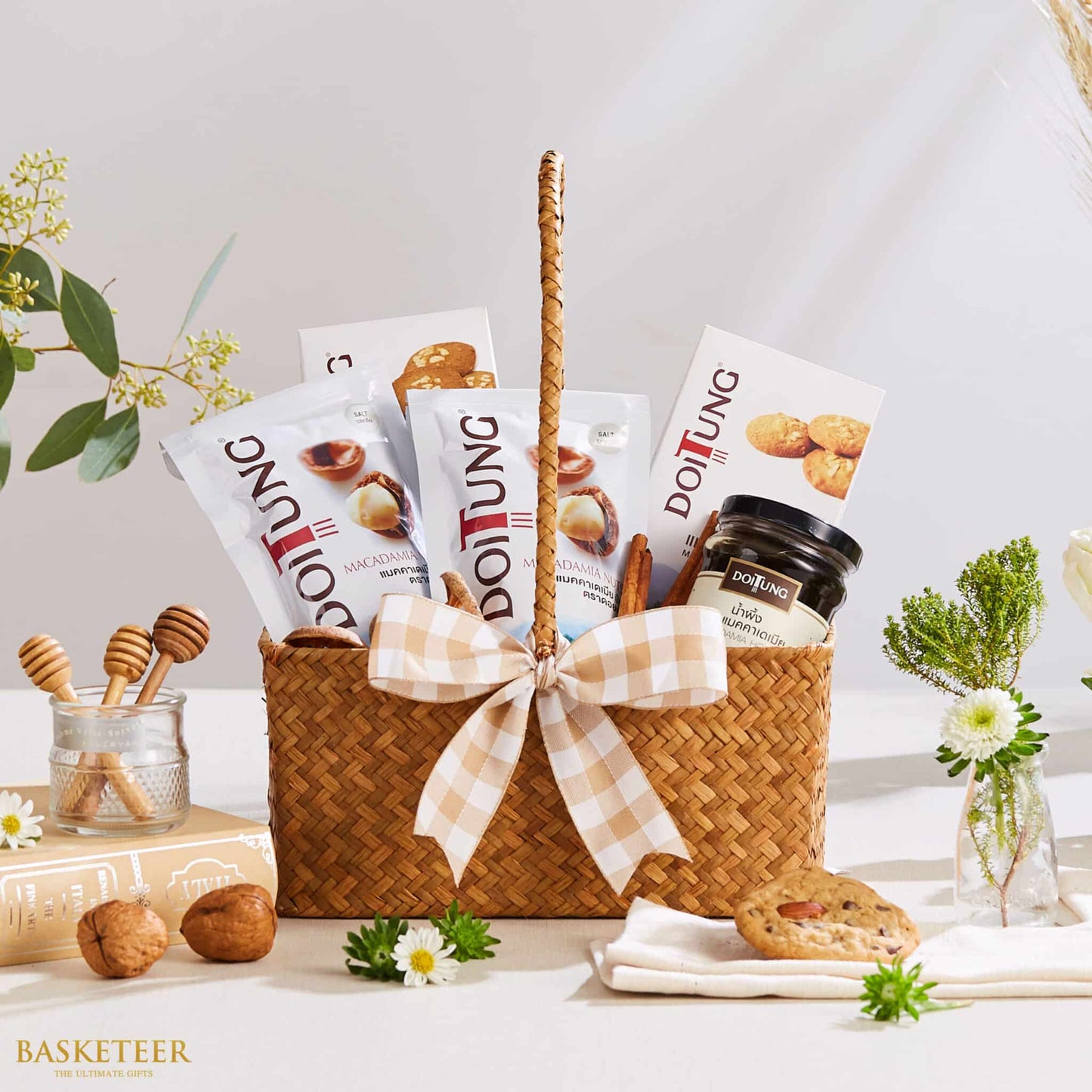 Woven gift basket with Doi Tung macadamia nuts, cookies, honey jar, and wooden dippers tied with gingham ribbon