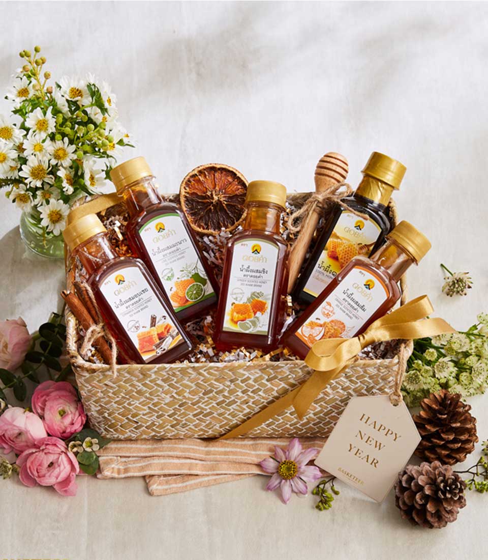 Woven honey gift basket with six glass bottles of pure Doi Kham honey, dried citrus, cinnamon, and wooden dipper, decorated
