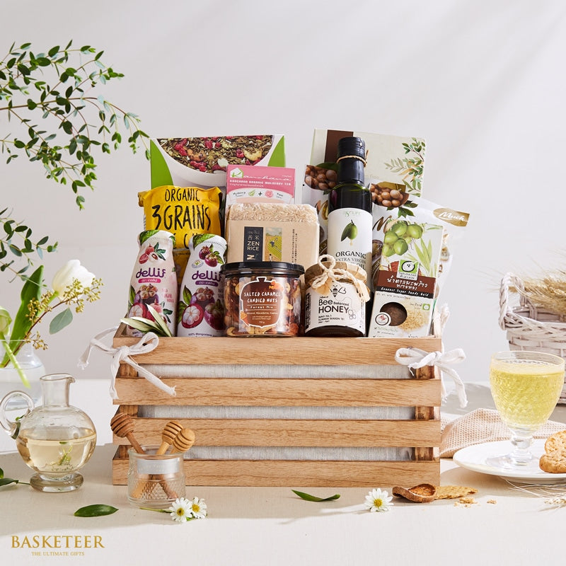 Organic Thai food gift basket with grains, honey, olive oil, and nuts in wooden crate with white ribbon