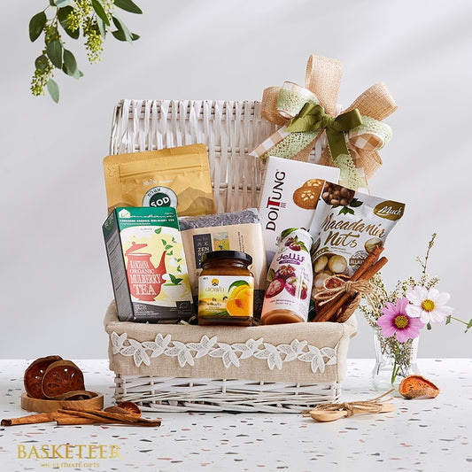 White wicker gift basket with Thai gourmet treats, burlap bow, organic tea, mango jam, and macadamia nuts