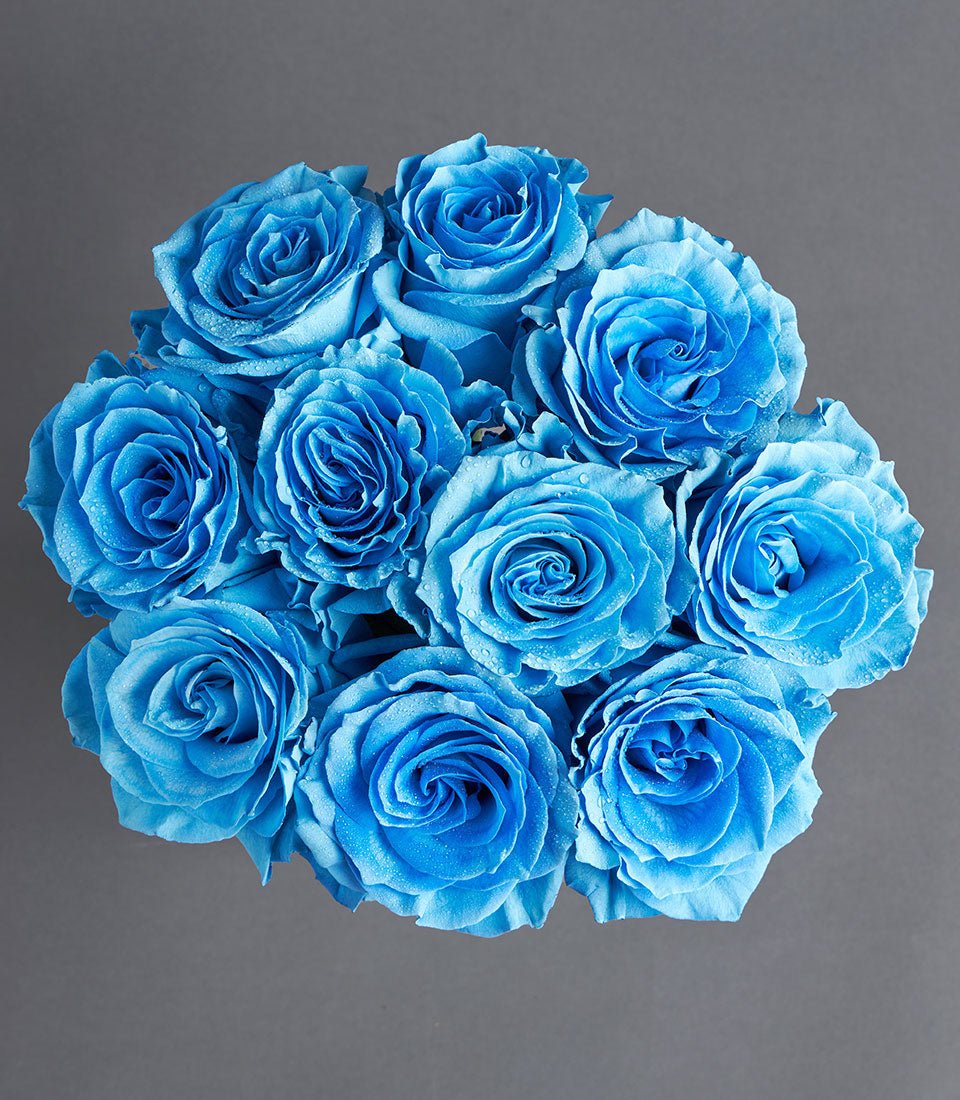 An elegant bouquet of fresh, vibrant blue roses with delicate water droplets, perfect