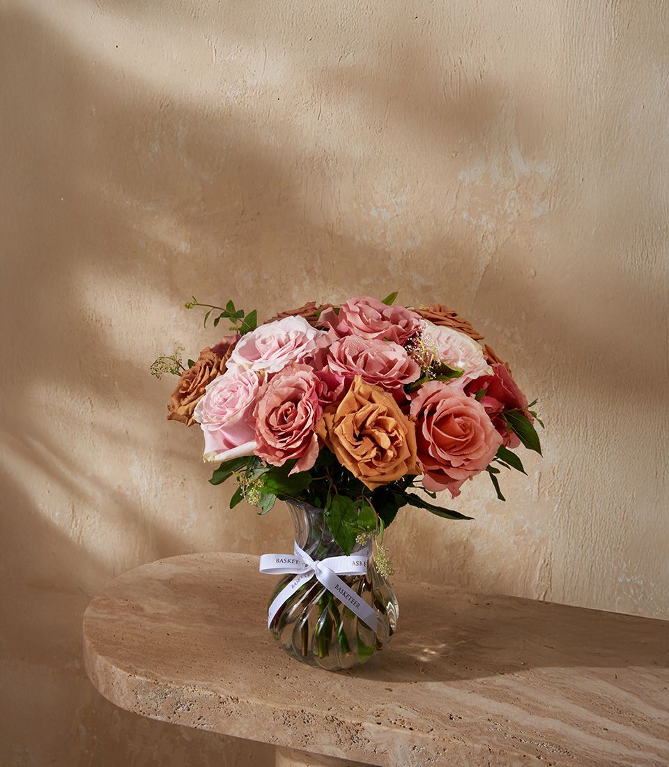 Luxe velour roses in pink, peach, and bronze with white filler in clear glass vase